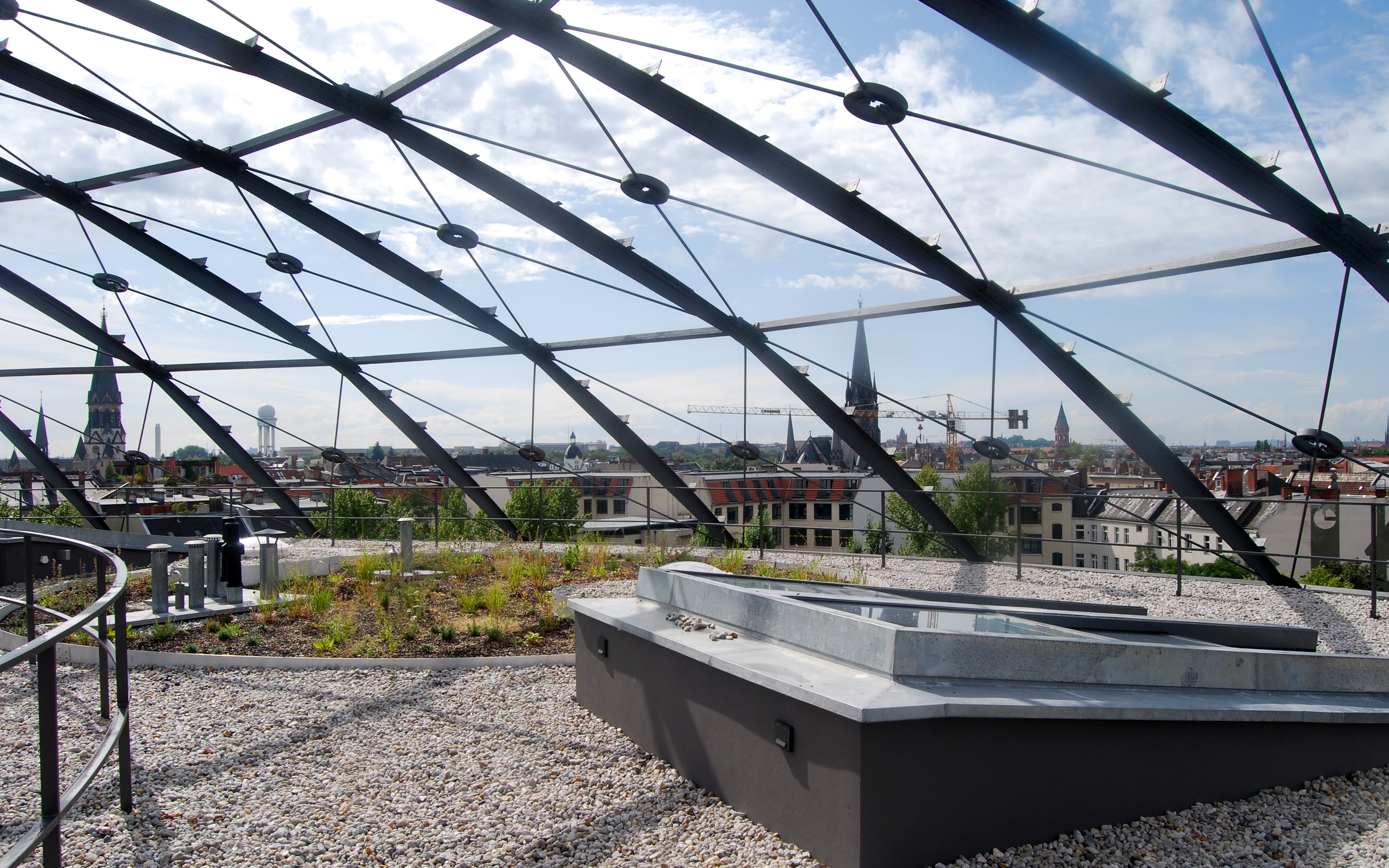 Dach mit Kies und extensiv begrünten Pflanzbereichen unter Stahlkuppel