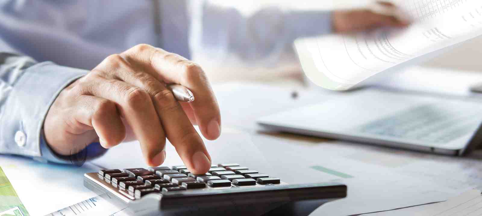 Person mit Taschenrechner am Schreibtisch